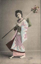 A Geisha lady holding a stick with flowers Postcard