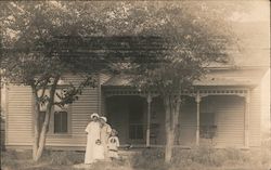 Two Women and Two Children Standing in Front of a White House. Postcard