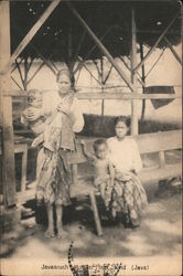 Two women wearing blouses and sarongs with their children Postcard