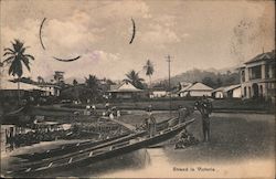 Men unloading fish from long rowboats propped up against a pier Postcard
