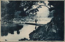 A person crossing a footbridge across a river Postcard