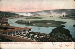 Small body of water surrounded by a hotel and houses Postcard