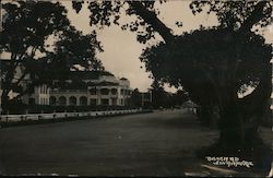 A coastal highway with a colonial building Postcard