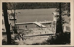 People standing on a beach overlooking a dock Postcard