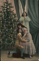 A Merry Christmas Man and Woman in Front of an Angel and a Christmas Tree Postcard