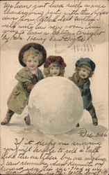 3 children playing in the snow rolling a large snowball. Postcard