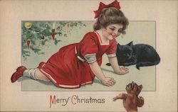 A child playing on the floor beside a chat under a christmas tree Postcard