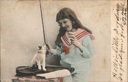 A kitten sitting on top a violin with a girl holding a violin bow Postcard