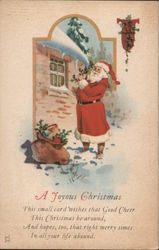 A Joyous Christmas - Santa Standing by a House in the Snow Postcard