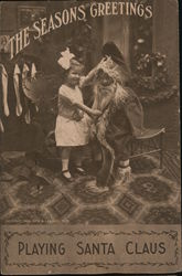The Seasons Greetings - A Little Boy Dressed as Santa and a Little Girl Pulling His Beard Postcard