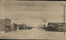 Main street view of snow covered town, Telephone/electrical poles Postcard