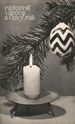 White candle on stand, in front of pine tree with ornament Postcard