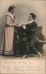A woman standing next to a bench is adressed by a seated man Postcard