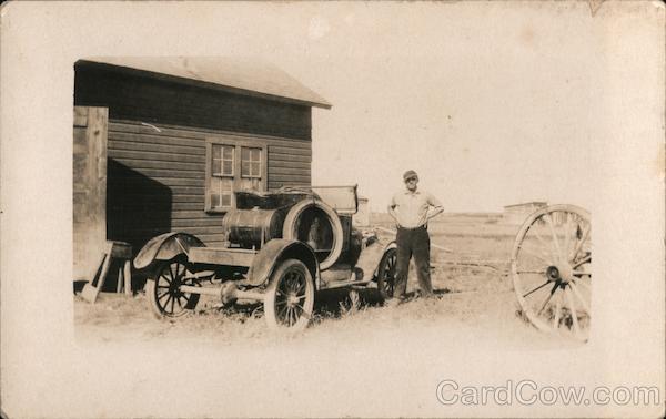 Antique car, wooden building, man, wooden wagon wheel vehicle