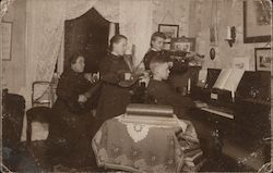 A family of four performing musical instruments together. Postcard