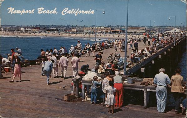 People fishing off ocean pier, beach Newport Beach California