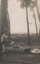 Woman Looking at Photo Album Under Trees Postcard