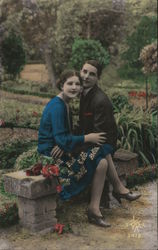 Young couple sitting on a bench in an French garden - in coor France Art Deco Postcard Postcard Postcard