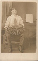 Man sitting on a chair playing the Accordion Postcard