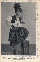 When a girl puts on a man´s hat it´s a sign she wants to kiss him. Postcard