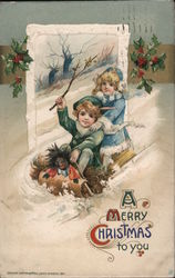A boy and girl with a doll sliding down a hill on a sled - A Merry Christmas to you Children John Winsch Postcard Postcard Postcard
