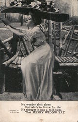 Woman in large floral hat sitting on a bench. Postcard