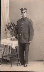 Fireman in Uniform Posing Next to a Table Postcard