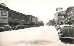 Street view photo on busy street, with shops and parked cars. Watsonville, Calif. Postcard