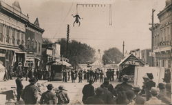 A Man Dangling Above a Crowd at an Attraction Postcard