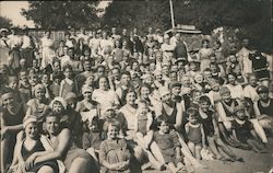 Large gGroup people posed on a beach with some in swimming gear Postcard