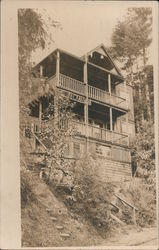Three story hotel on hillside in forest Postcard
