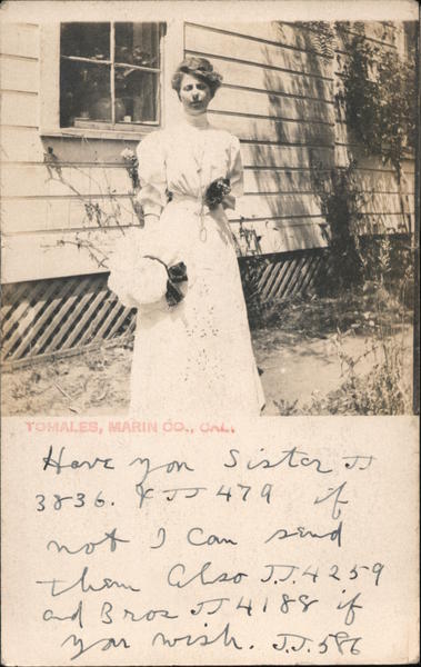 A Woman Holding her Hat Standing Next to a House Tomales California