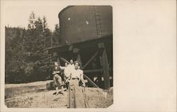 Four People Standing in front of a Water Tank Postcard