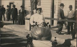 A Woman Pushing a Child in a Large Pumpkin Postcard