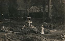 Woman walking by fountain in garden Postcard