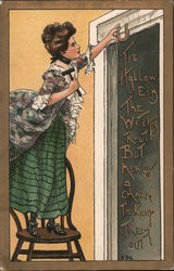 Tis Halloween. The witches rout but heres a charm to keep them out. Girl nailing horseshoe over door HBG Postcard Postcard Postcard