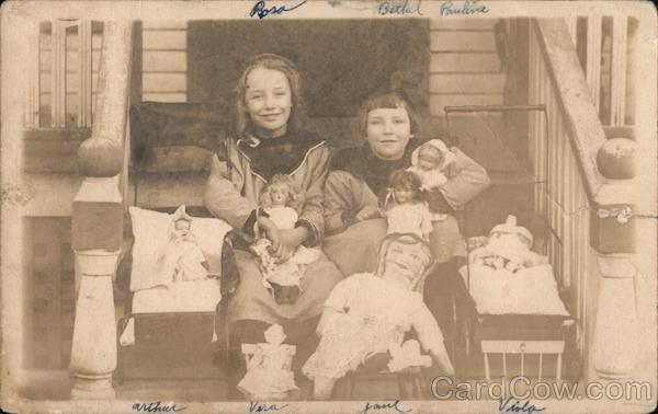 Two girls with several of their dolls