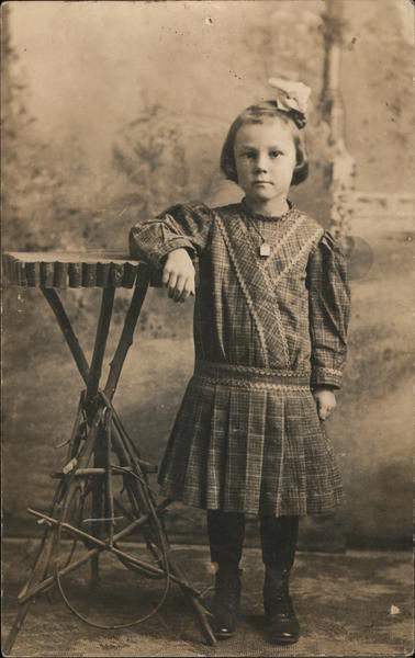 Studio portrait of young girl leaning on wooden table made with branches