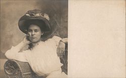 Portrait of woman sitting in rattan chair, big hat Postcard