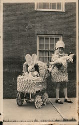 Stuffed bunny in decorated baby buggy with girl and tall doll Postcard