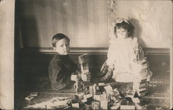 Children playing with blocks and dolls on floor Postcard