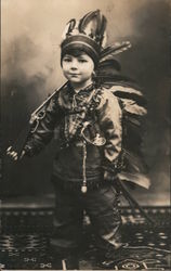 Little boy dressed in Indian Costume with headdress with rifle and sword Postcard