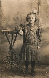 Studio portrait of young girl leaning on wooden table made with branches Postcard