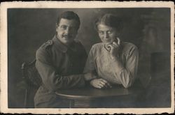 Couple seated at table. Man in uniform Postcard