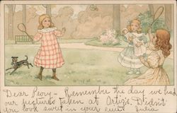 Two Girls playing badminton, while a third girl, with doll, watches Postcard