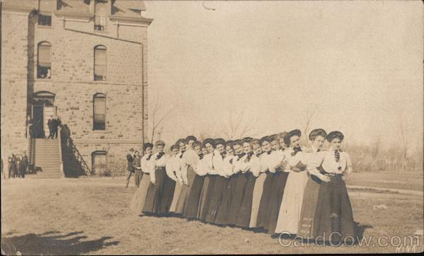 Row of young women in front of school.