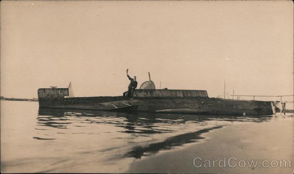 A man raises his hand, while seated on a docked submarine