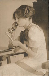 Young woman sits and talks on a telephone Postcard
