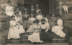 Ladies pose, seated on the steps of a stone building Postcard