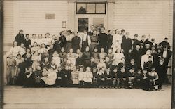 Group of people posing outside - in front of a Church or School Postcard